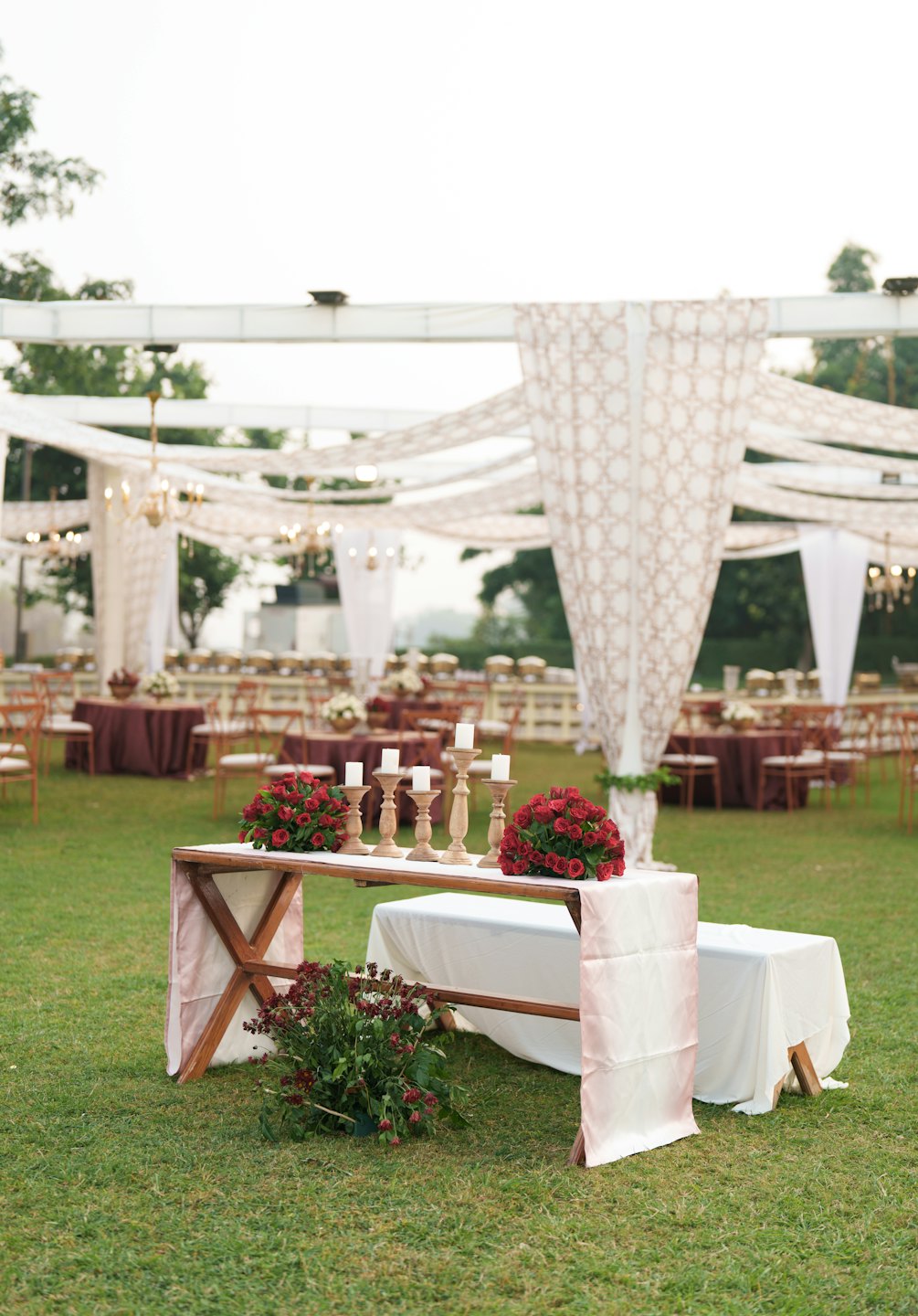 Decorated wooden table with flowers and candles at an outdoor event.
