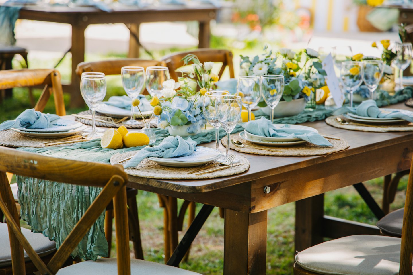 Rustic table set for an outdoor celebration with floral arrangements.