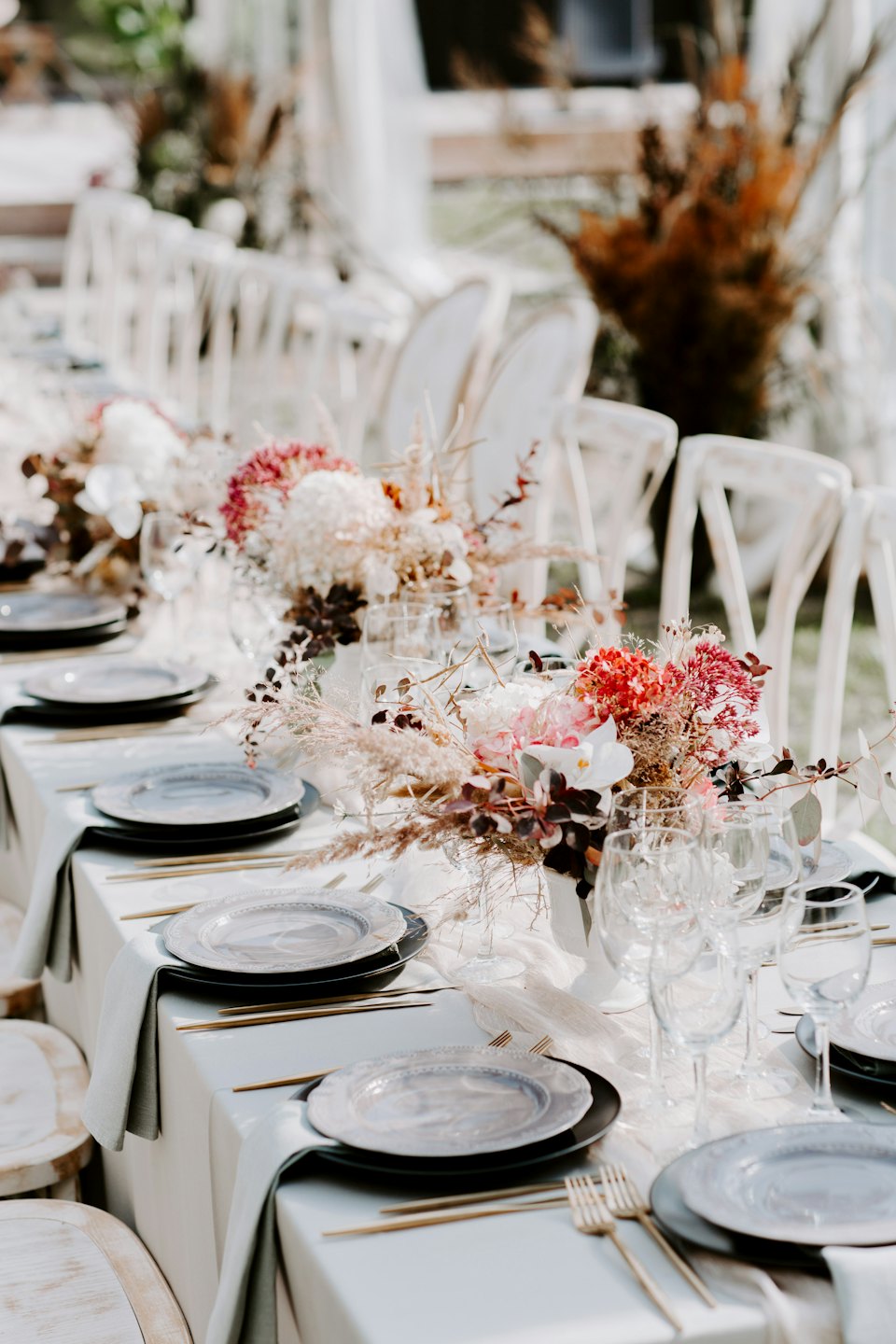 An outdoor dining table with elegant floral centerpieces and settings.