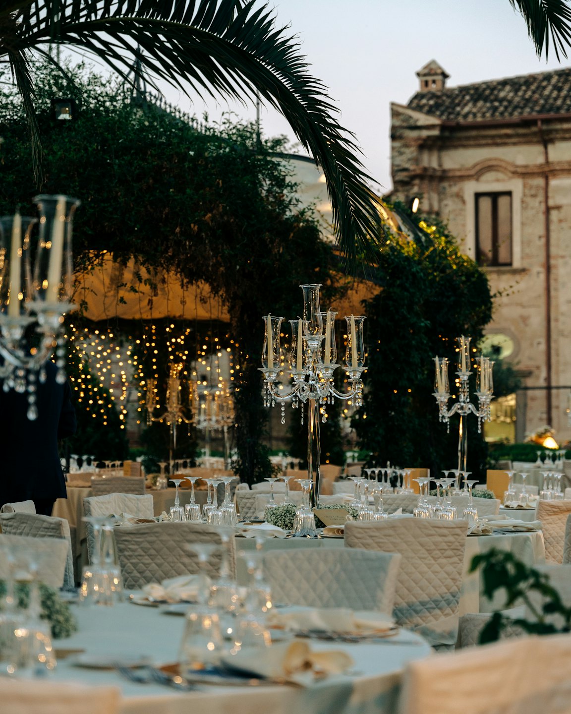 Elegant reception tables set outdoors near an ancient stone building.
