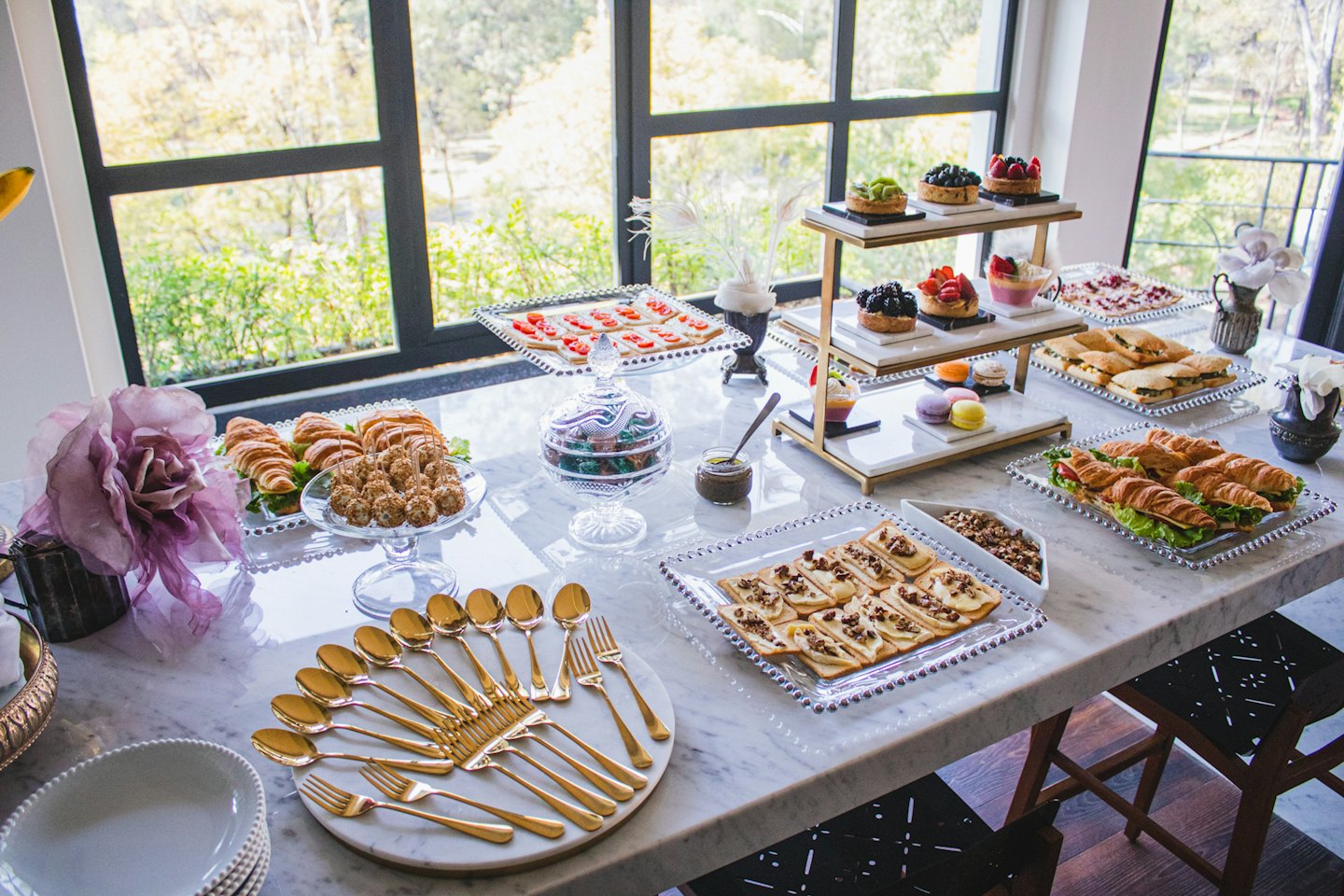 Elegant indoor buffet spread with pastries, sandwiches, and desserts on marble.