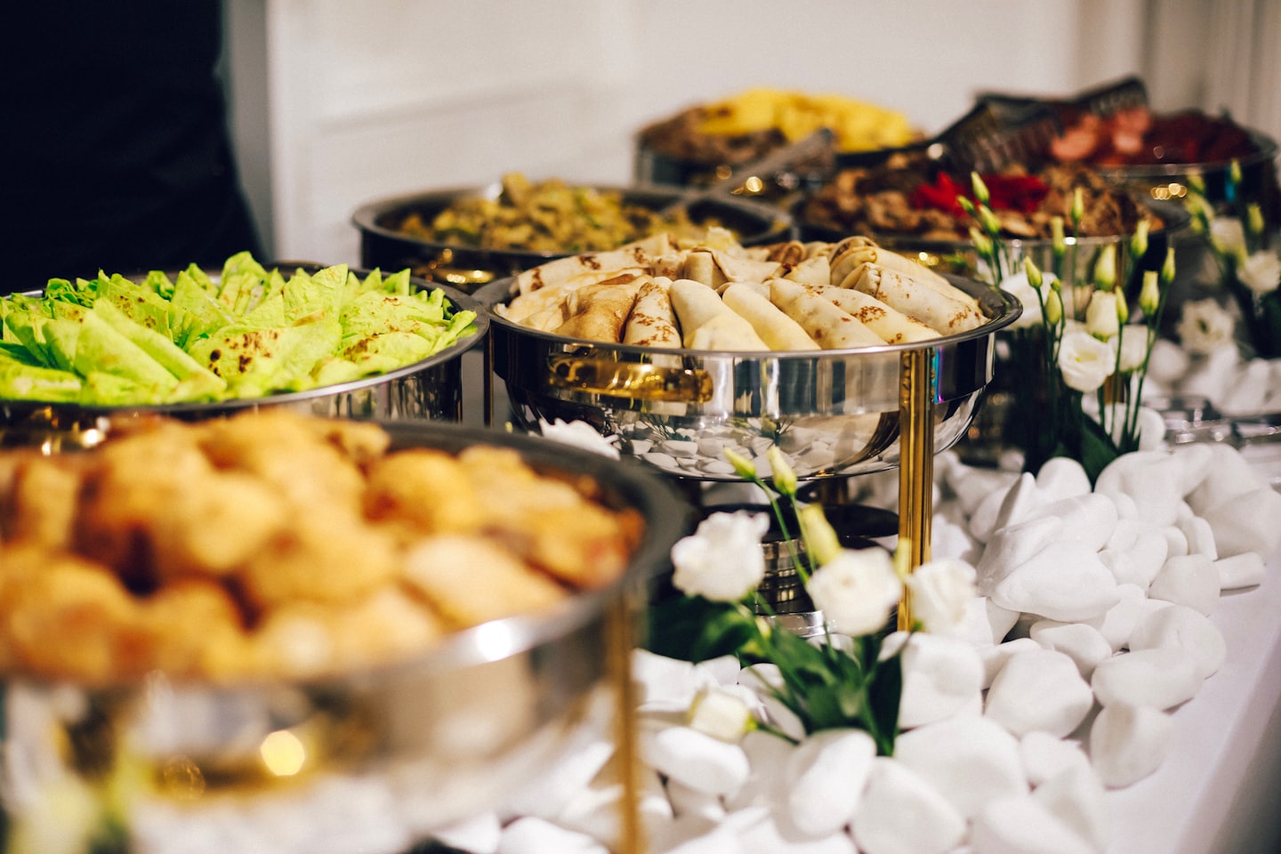 Buffet spread with various dishes in chafing dishes.