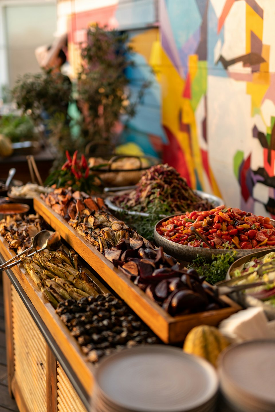 Fresh salads and roasted vegetables displayed on a wooden table outdoors.