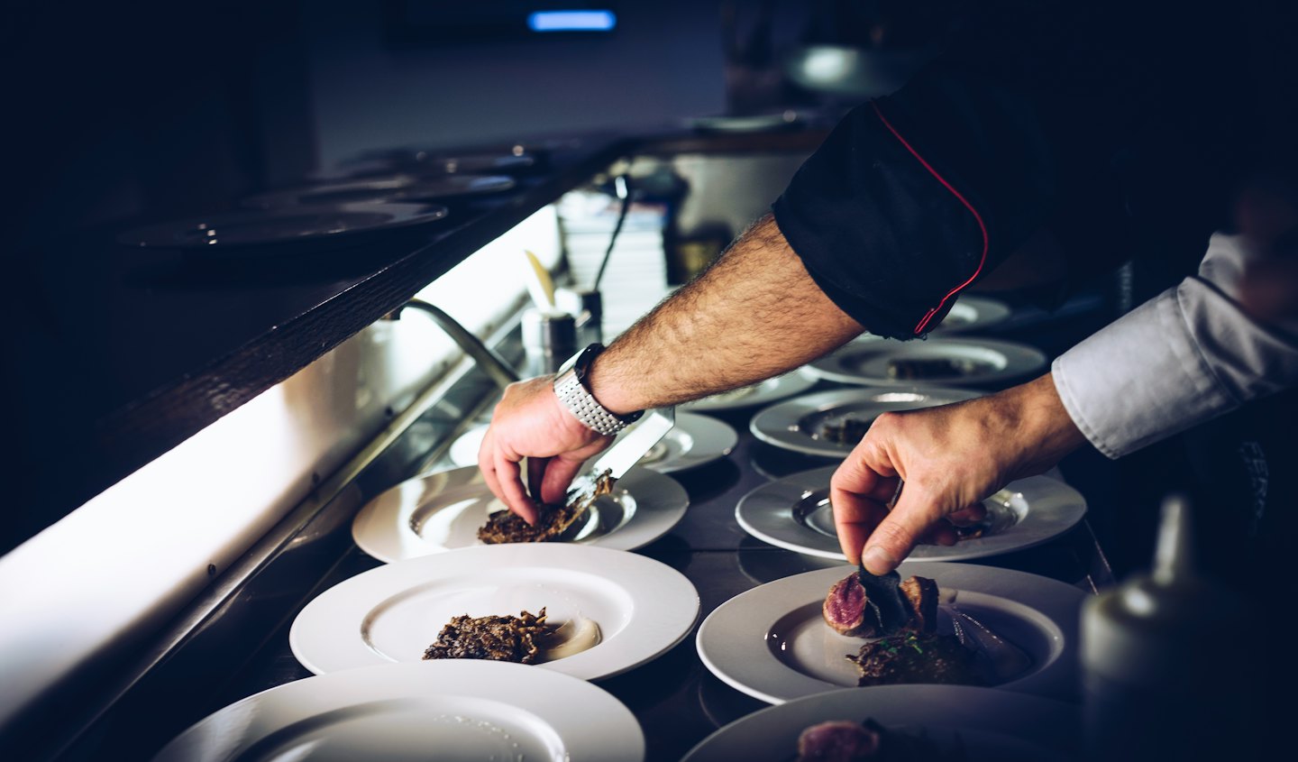 Chef meticulously plating gourmet dishes in a commercial kitchen.