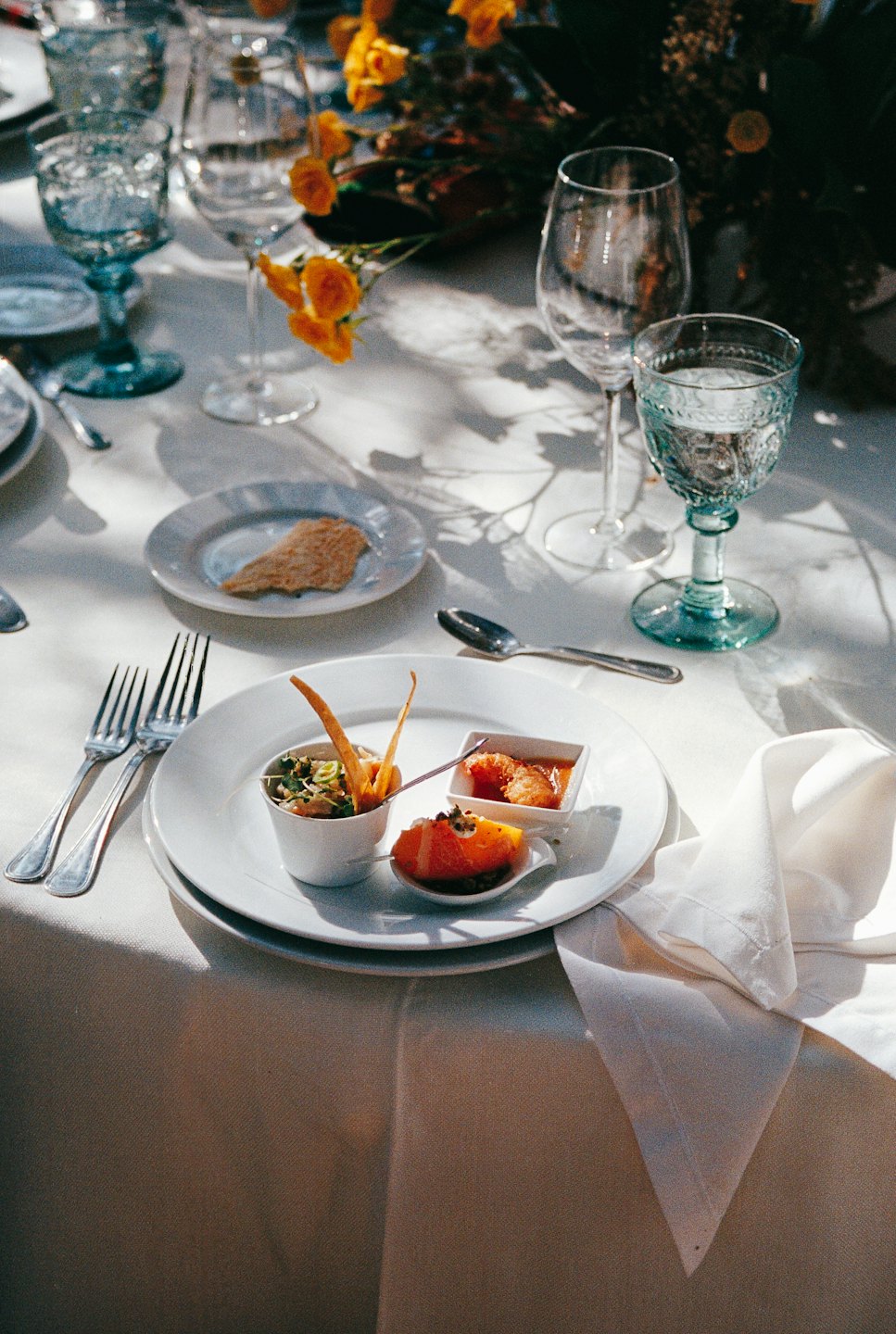 Table set with gourmet appetizers and orange floral centerpieces.
