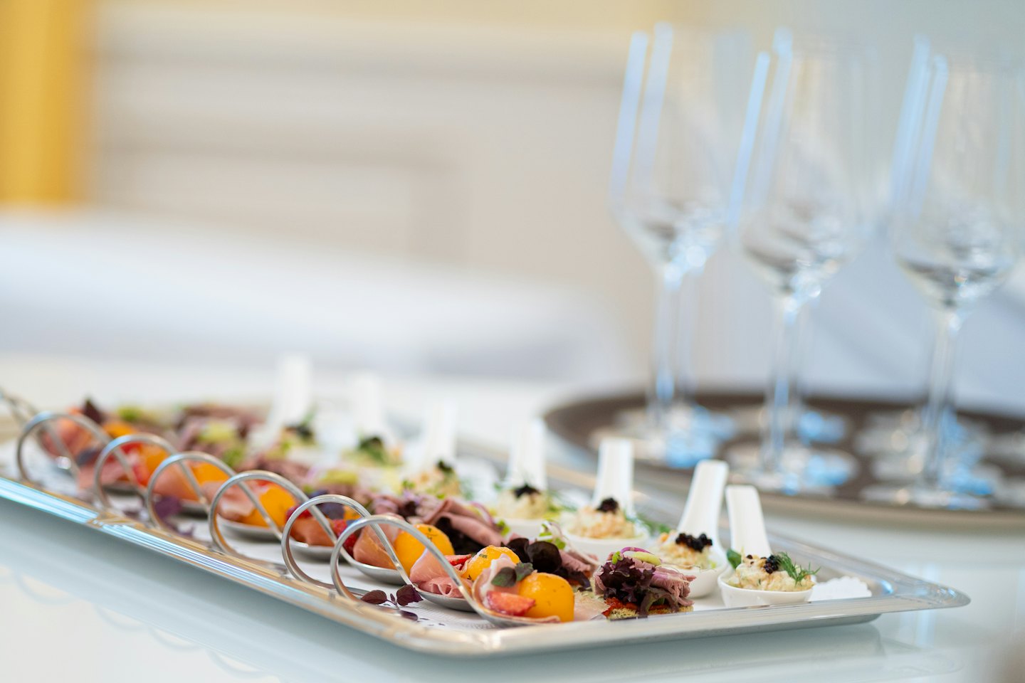 Gourmet canapes served on white spoons arranged on a tray.