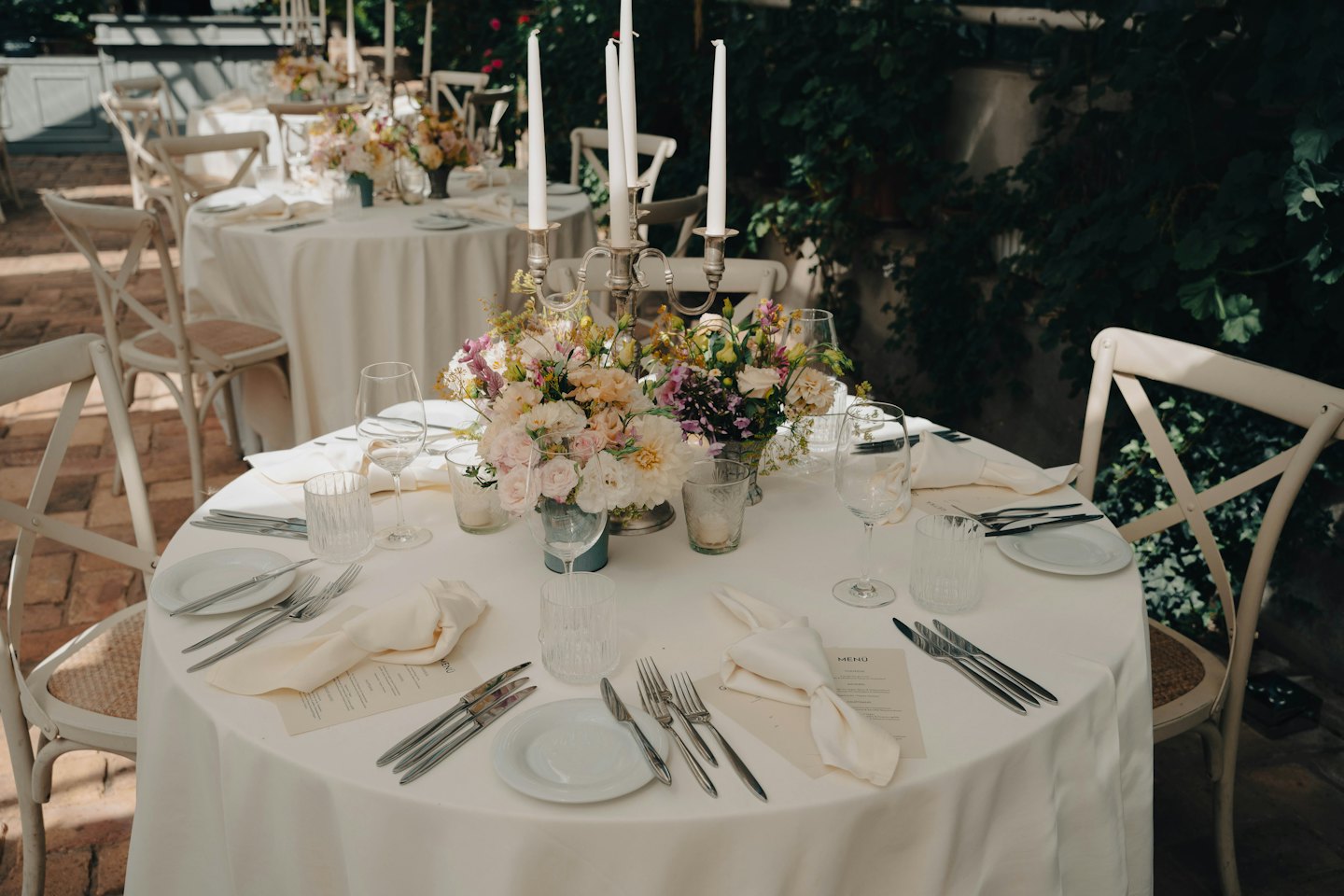 Elegant outdoor table setting with flowers and candelabra.