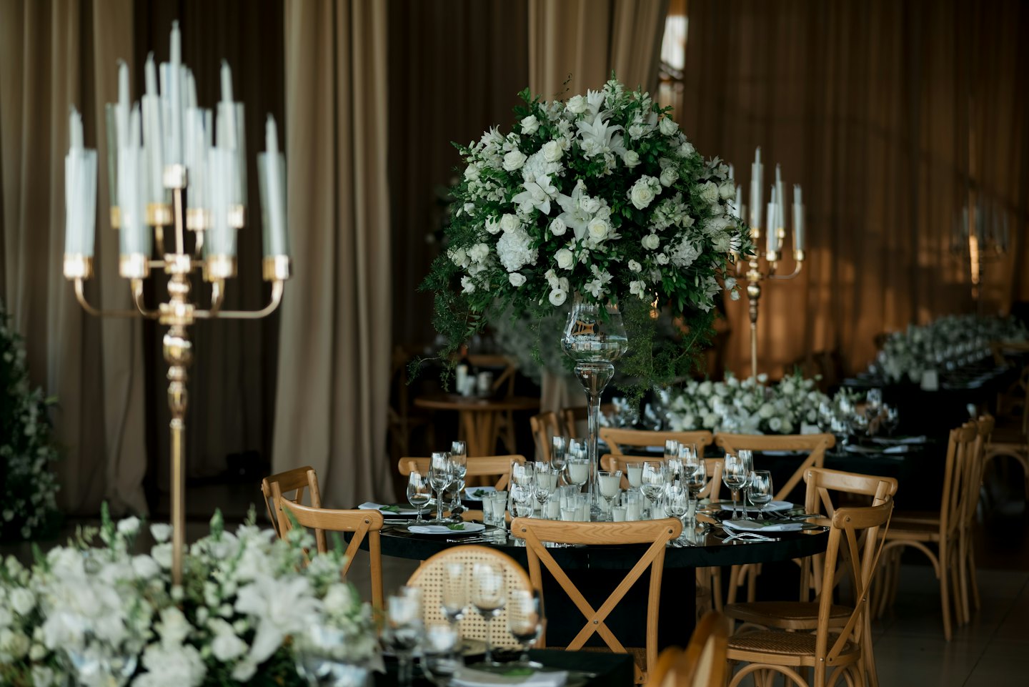 Elegant round tables set for an event with floral centerpieces and golden candelabras.