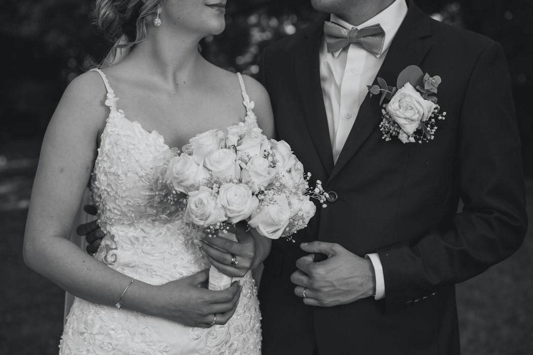 A bride and groom holding hands while wearing wedding attire.